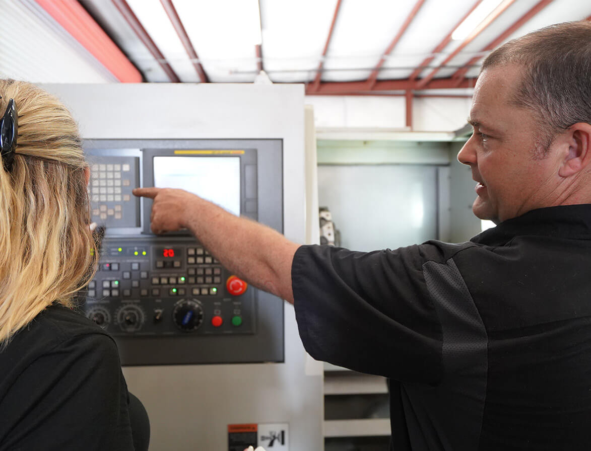 a guy showing a woman a CNC machine